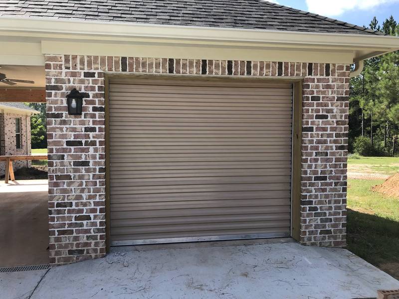 A tan roll-up door on a brick outbuilding.